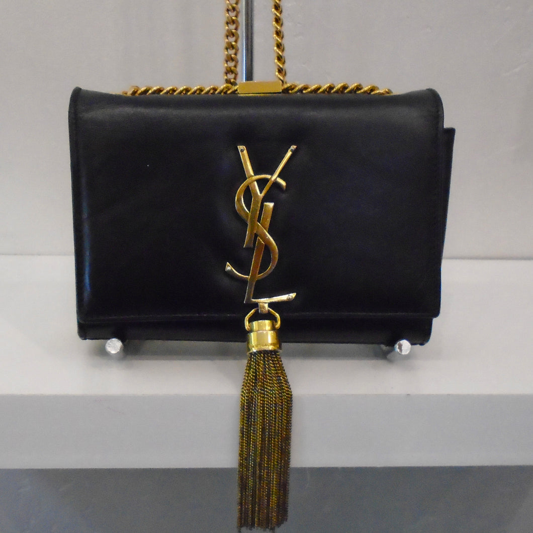This YSL Kate Black Leather has gold hardware which includes the letters YSL on the front flap of the bag, a tassle at the bottom of the front flap and a long shoulder chain.
